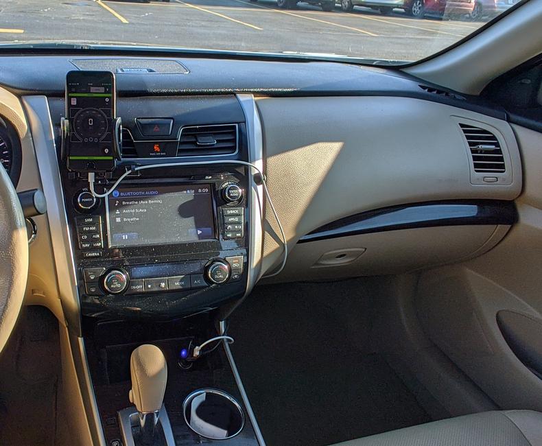 An image of the center control stack in the interior of a car, with a phone charging cable routed around the perimeter of the controls.