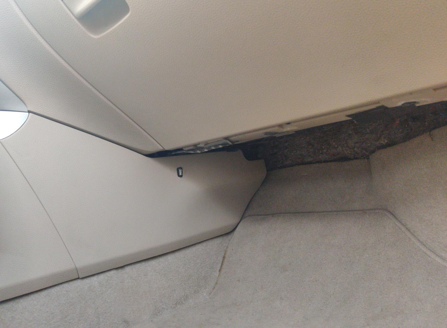 A discrete USB port in the passenger footwell of a car.