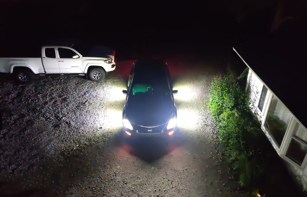 Overhead view of a sedan in the dark with the headlights and 4 perimeter lights illuminating the surrounding area.