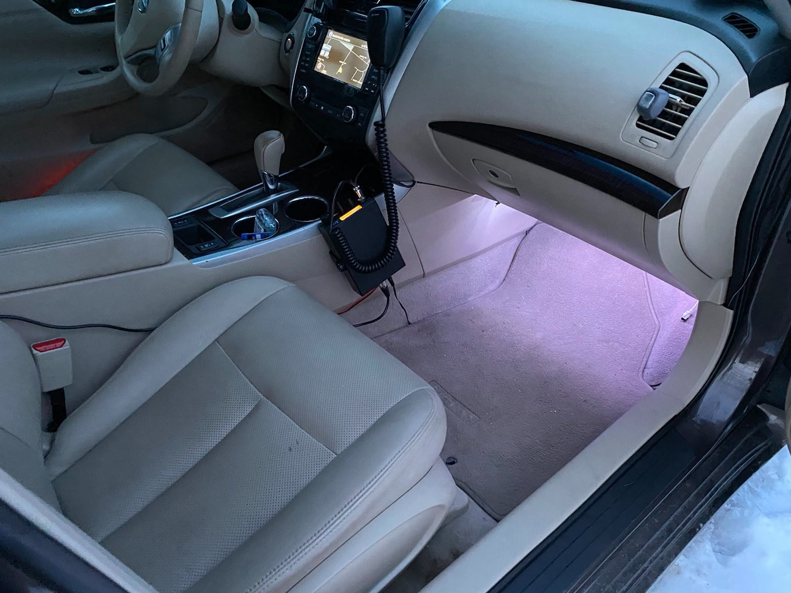 A concealed light strip in the passenger footwell of a car, displaying plain white