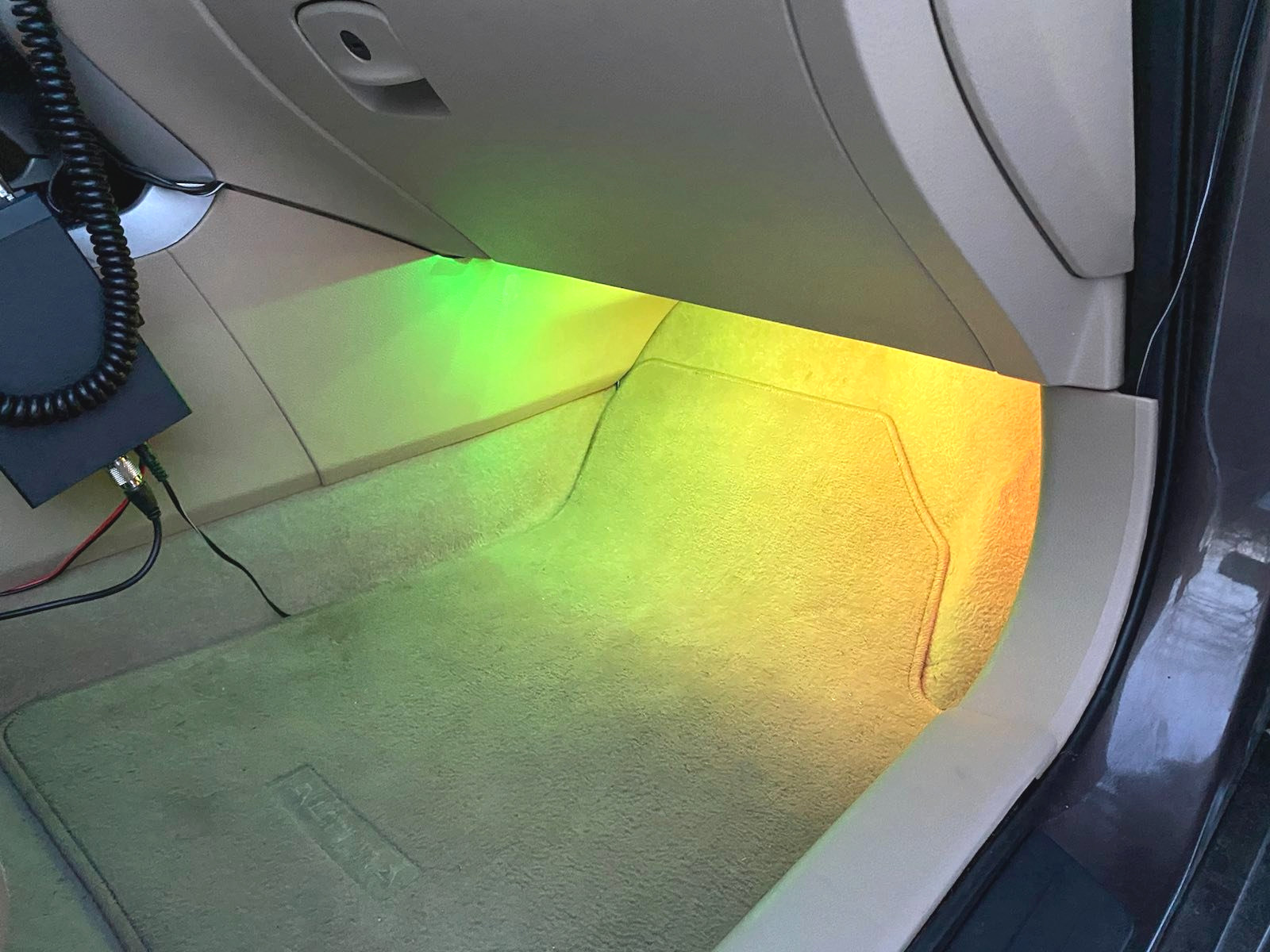 Colorful lighting in the passenger footwell of a car, clear visible despite a bright surrounding environment