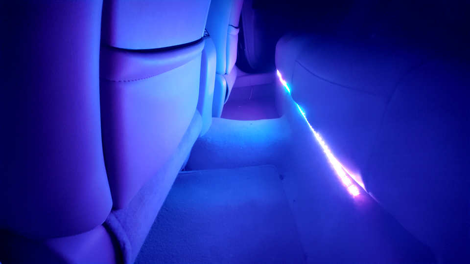 Smooth blue and purple light from a interior mood lighting system filling the backseat of a car with vibrant colors