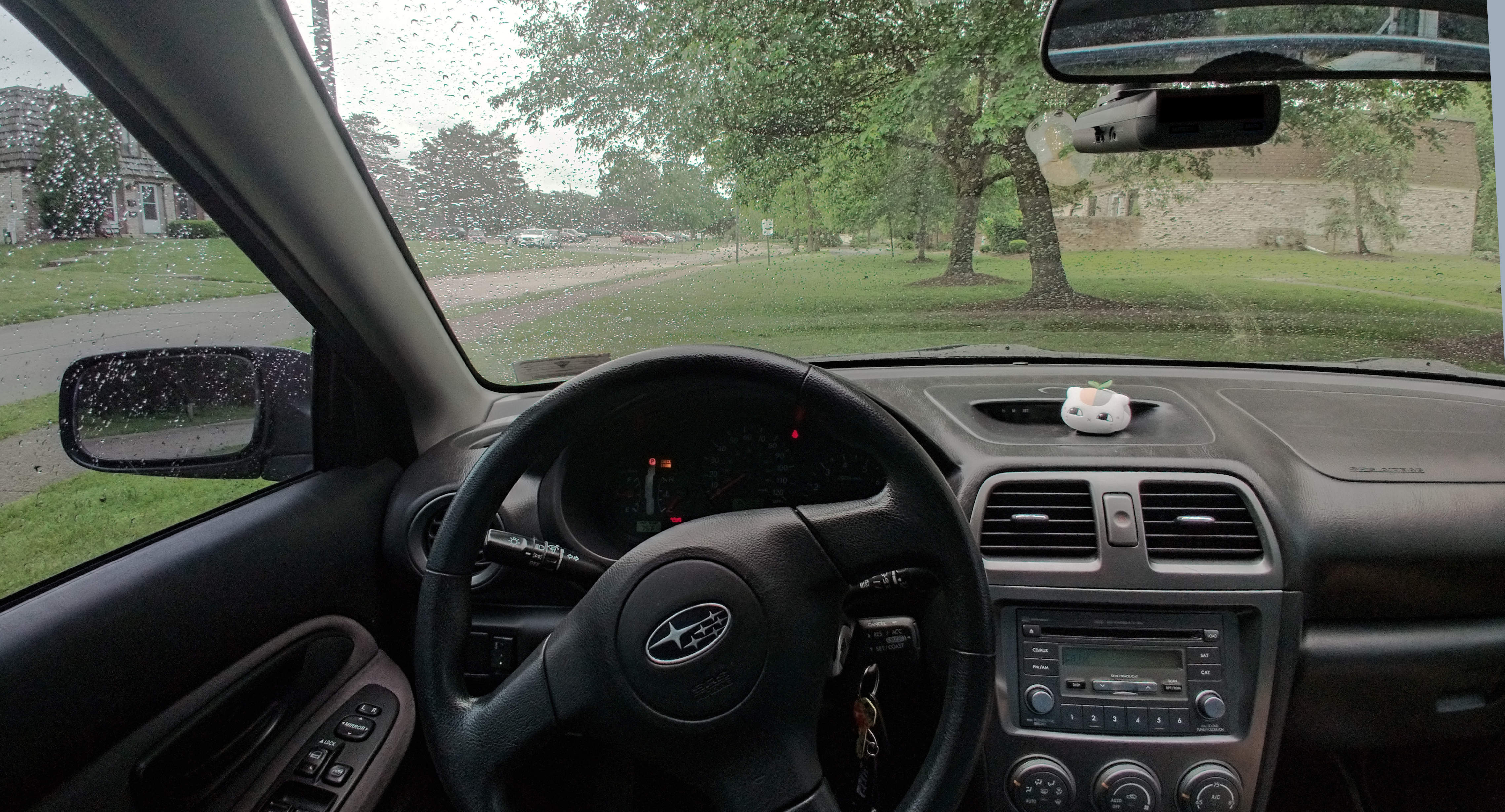 The interior of a car from the perspective of the driver, showing a discrete radar detector on the underside of the rear view mirror