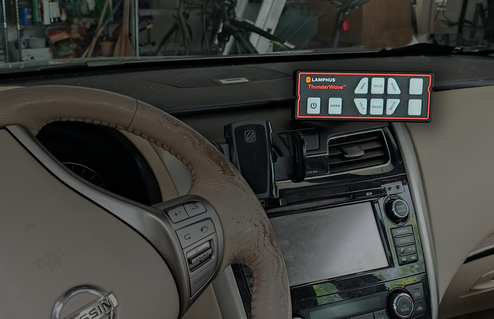 A highlighted siren control panel install above the center of the dashboard in a sedan interior