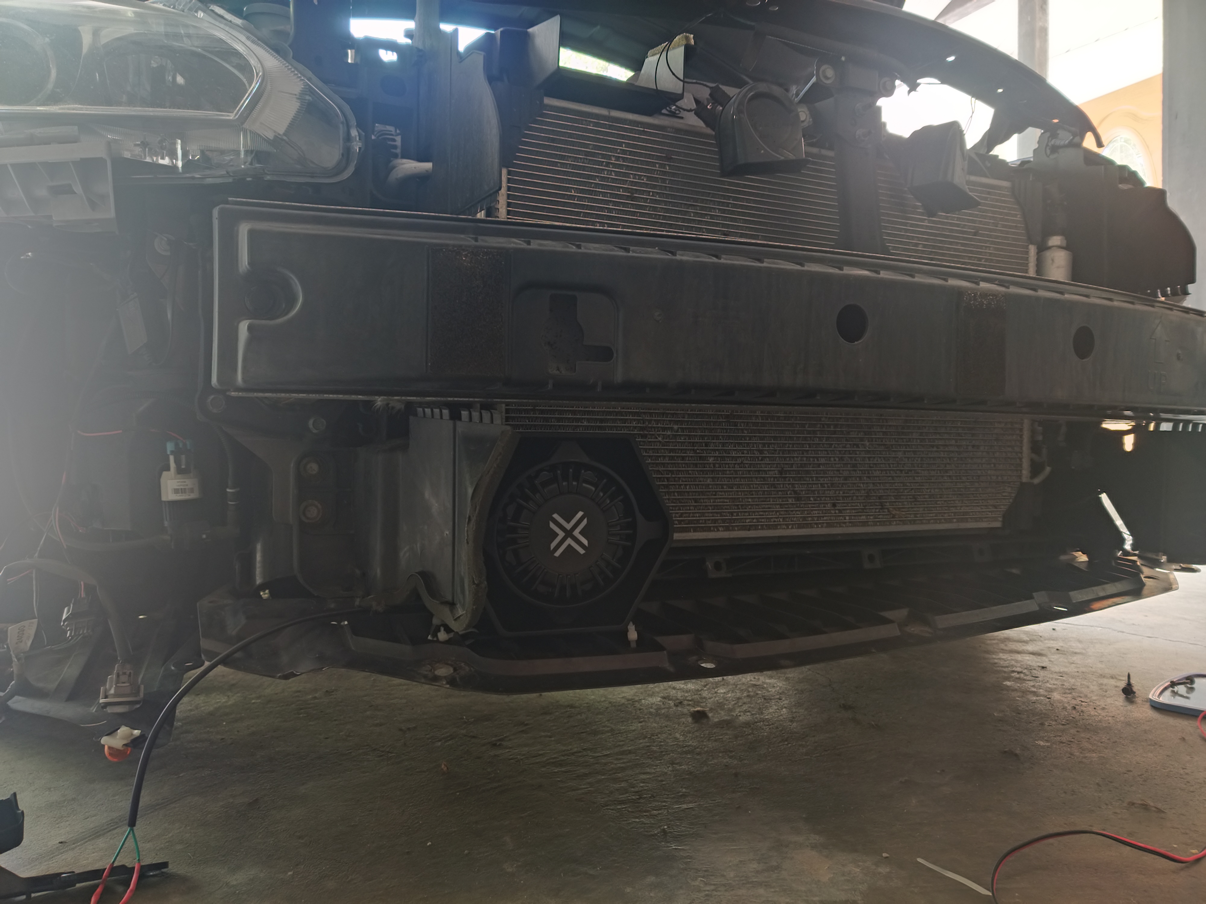 A sedan with the bumper removed, revealing a 6 by 6 inch siren speaker