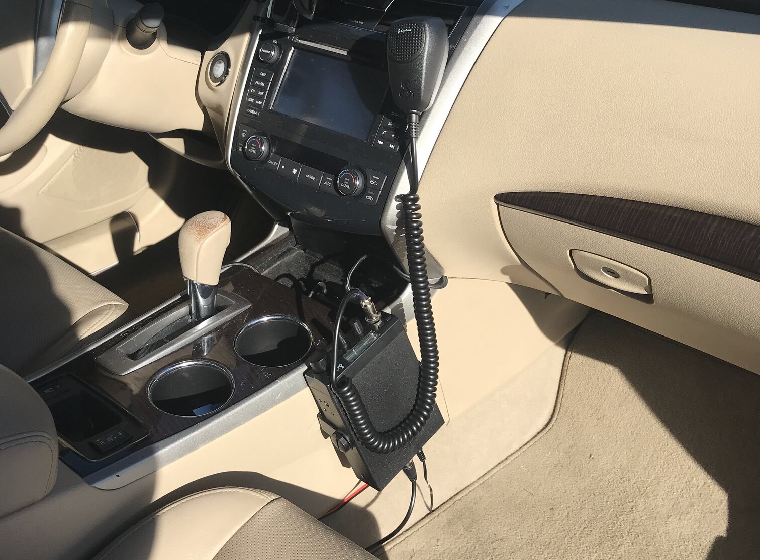 A two-way, citizen-band radio installed on the side of the center console in a sedan