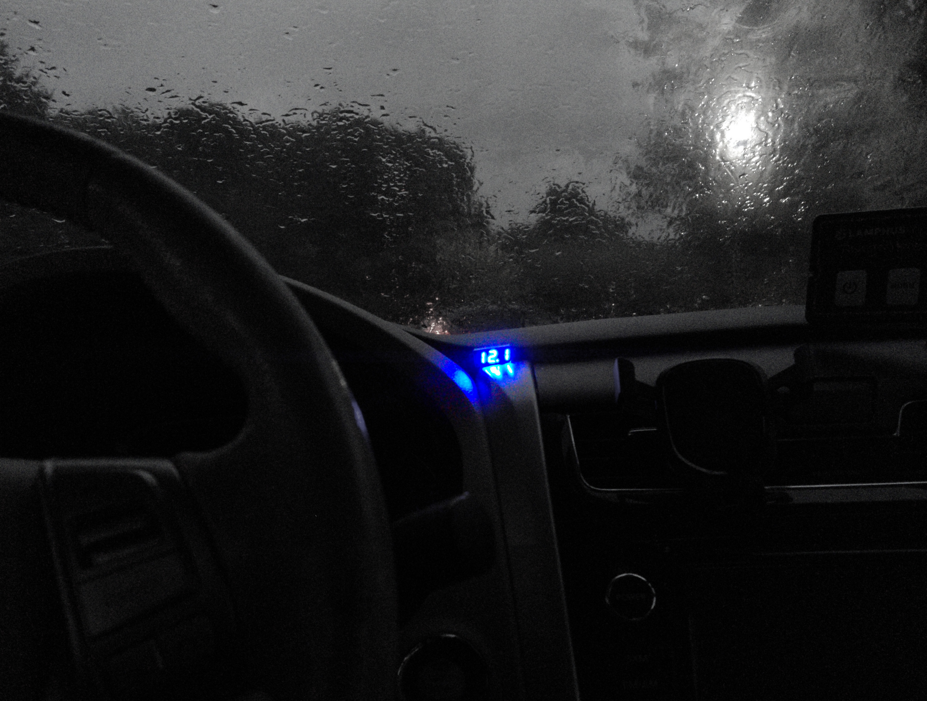 A dark image of a car interior with a vibrant blue 7-segment display depicting the number 12.1.